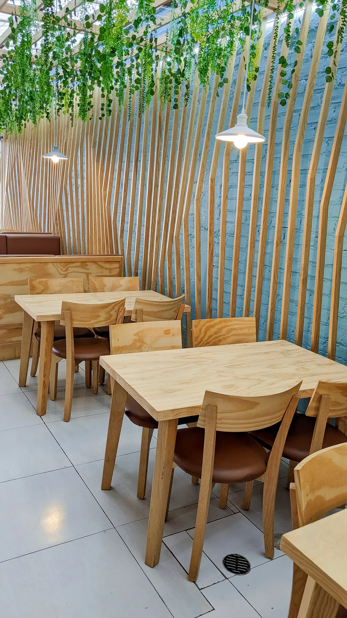 Square image of dining area with hanging plants and wooden slats